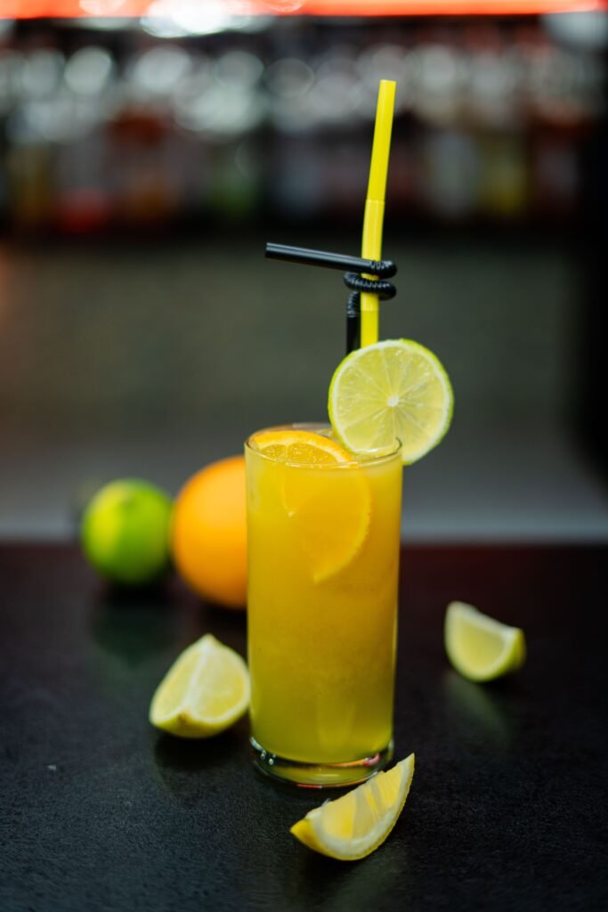 Vibrant citrus cocktail garnished with lime and orange on a bar counter.