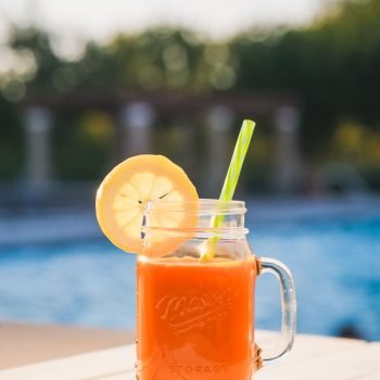 Delicious orange juice in a mason jar with lemon slice by the pool for a refreshing summer drink.